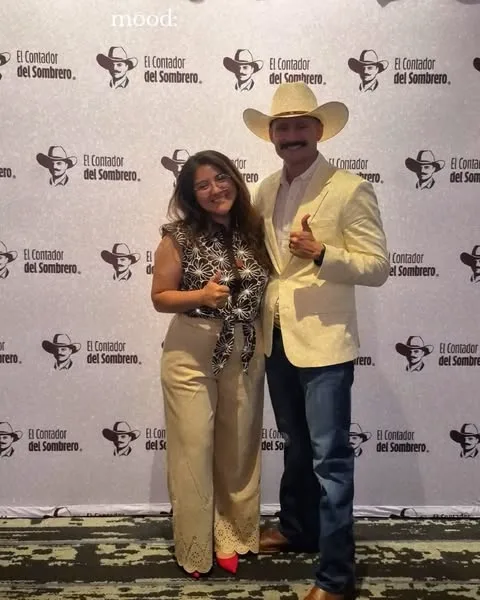 Marcos Ramirez junto a una asistente frente al backdrop de El Contador del Sombrero.